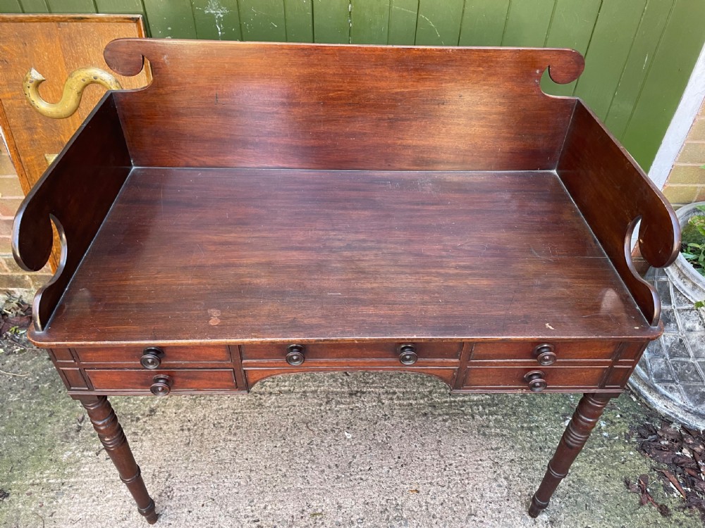 An early 19th-century George III mahogany kneehole dressing table with a scroll-ended three-quarter gallery back, multiple drawers, and ring-turned legs. View IV
