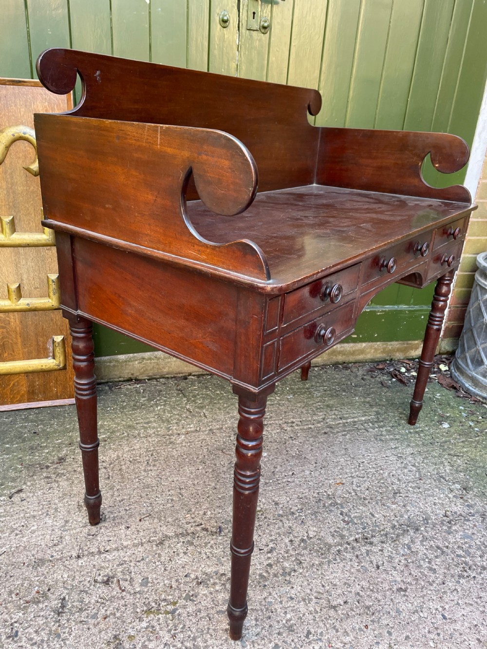 An early 19th-century George III mahogany kneehole dressing table with a scroll-ended three-quarter gallery back, multiple drawers, and ring-turned legs. View V