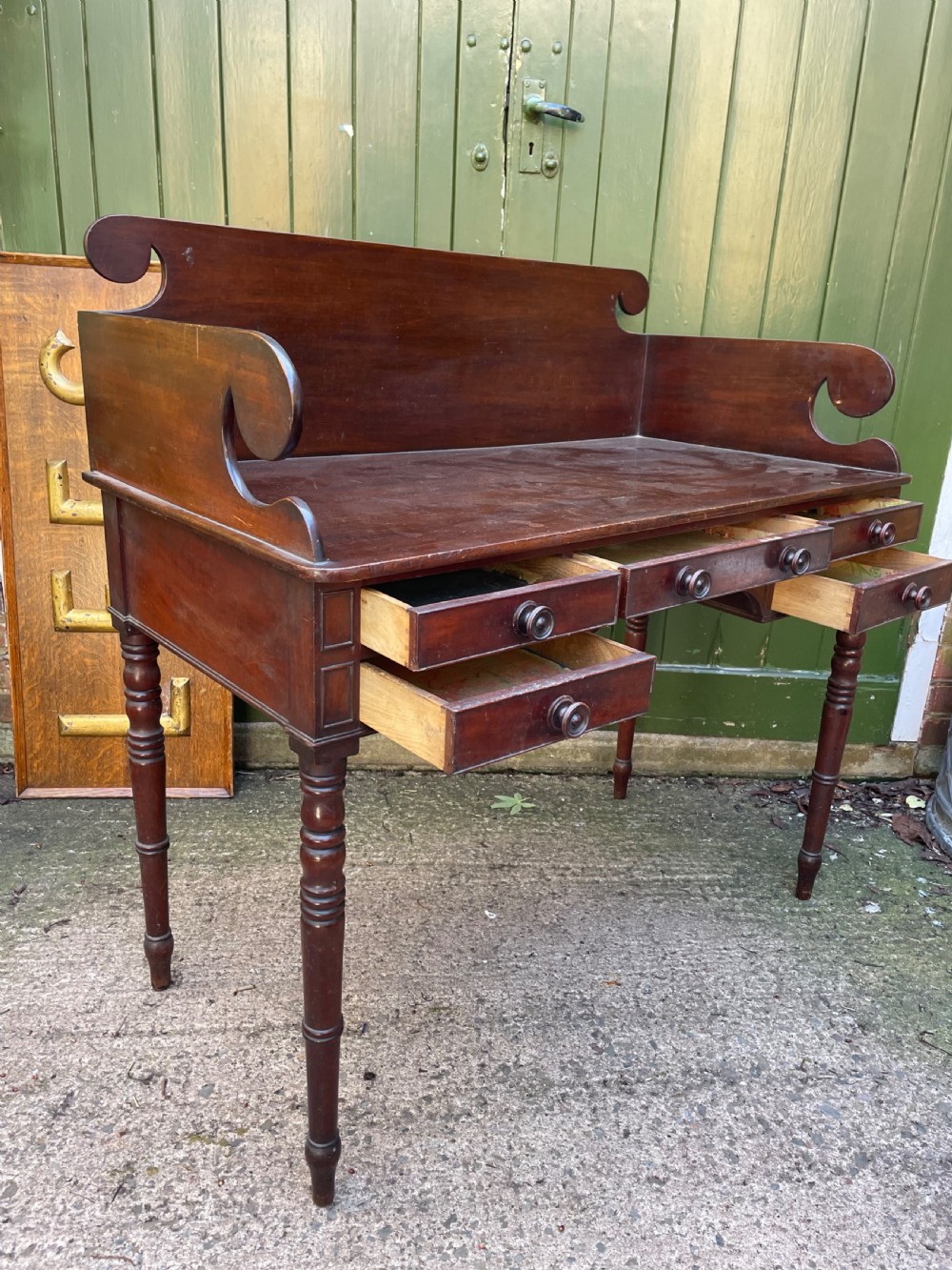 An early 19th-century George III mahogany kneehole dressing table with a scroll-ended three-quarter gallery back, multiple drawers, and ring-turned legs. View VI