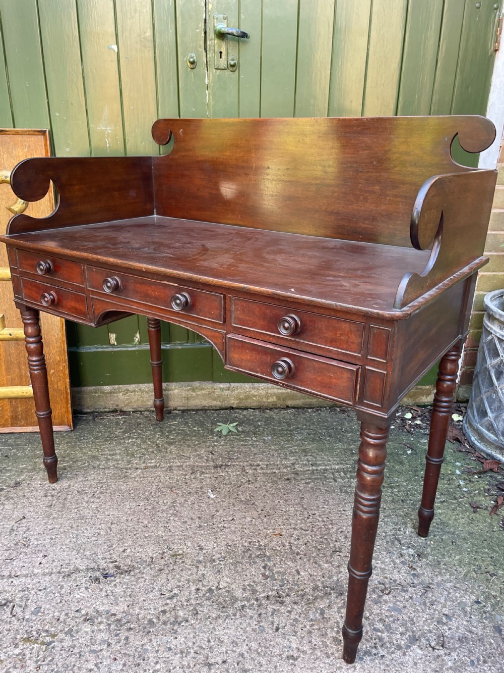 An early 19th-century George III mahogany kneehole dressing table with a scroll-ended three-quarter gallery back, multiple drawers, and ring-turned legs. View XII