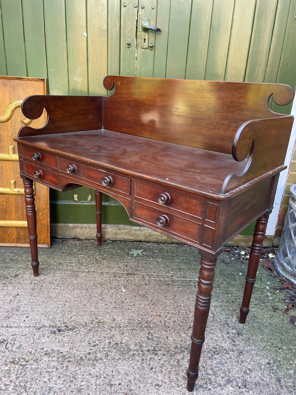 An early 19th-century George III mahogany kneehole dressing table with a scroll-ended three-quarter gallery back, multiple drawers, and ring-turned legs. View XIII