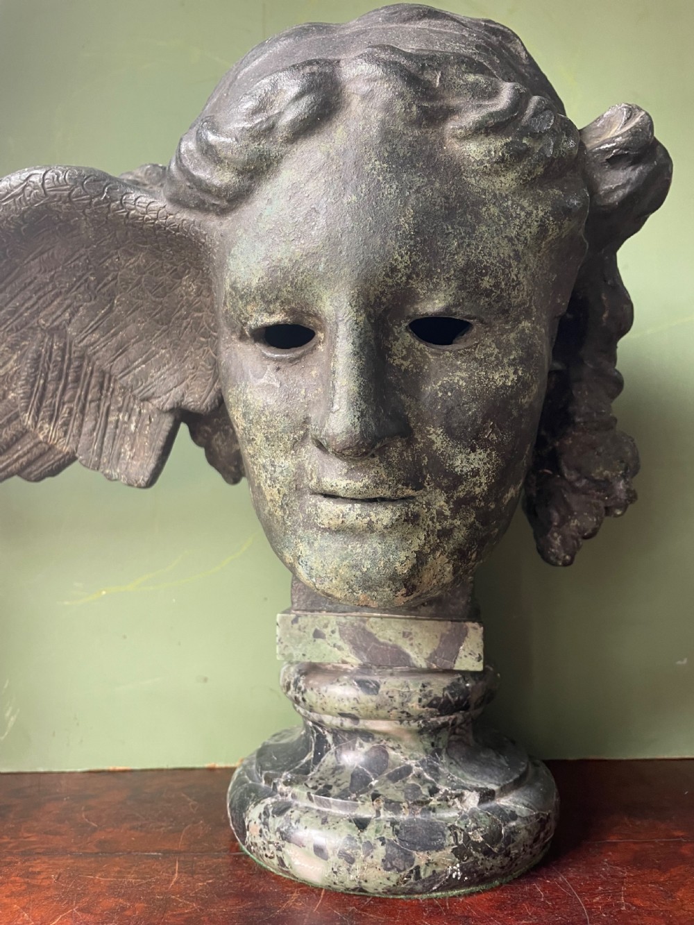 A 19th-century verdigris bronze head study of Hypnos featuring a winged temple, mounted on a round variegated green marble base. View II