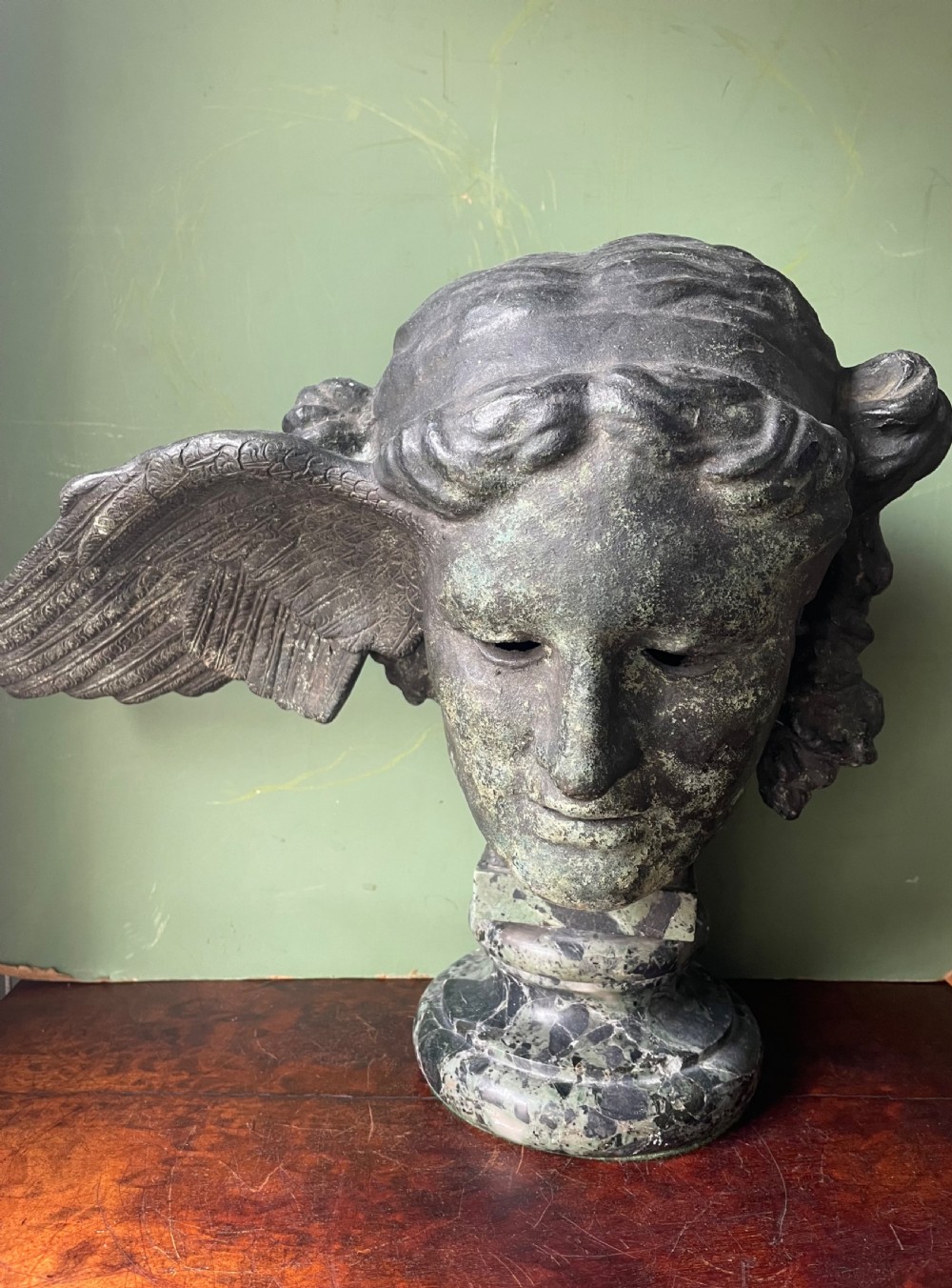 A 19th-century verdigris bronze head study of Hypnos featuring a winged temple, mounted on a round variegated green marble base. View III