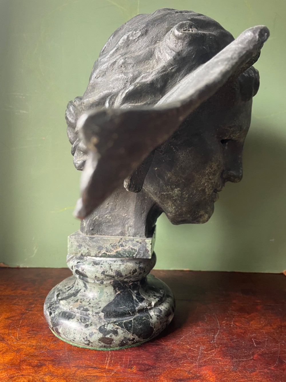 A 19th-century verdigris bronze head study of Hypnos featuring a winged temple, mounted on a round variegated green marble base. View VIII