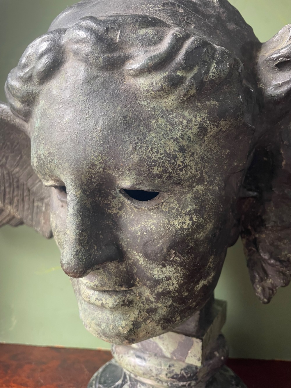A 19th-century verdigris bronze head study of Hypnos featuring a winged temple, mounted on a round variegated green marble base. View XIII