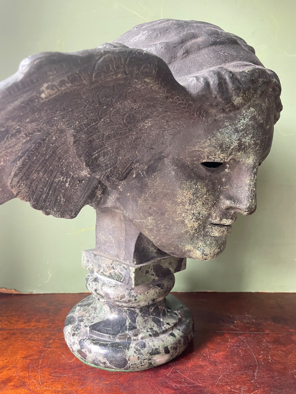 A 19th-century verdigris bronze head study of Hypnos featuring a winged temple, mounted on a round variegated green marble base. View XVIII