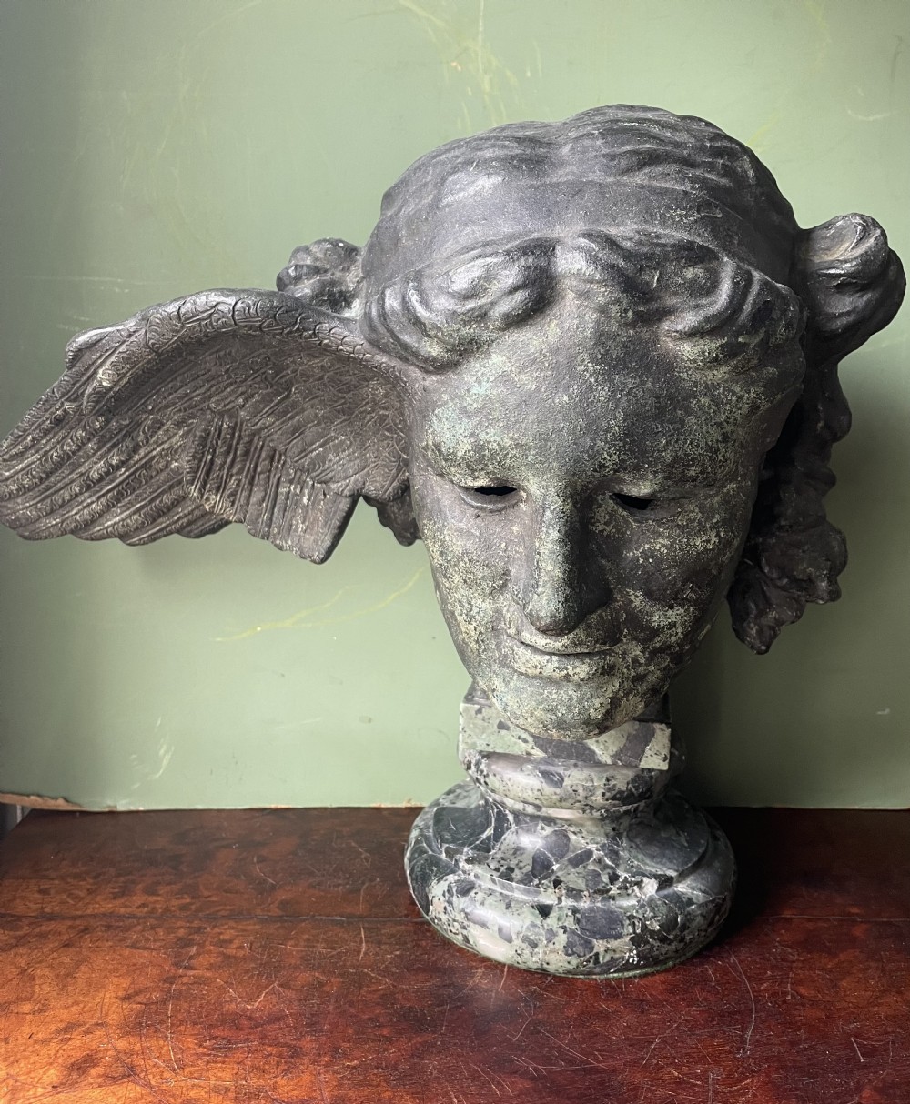 A 19th-century verdigris bronze head study of Hypnos featuring a winged temple, mounted on a round variegated green marble base. View XXII