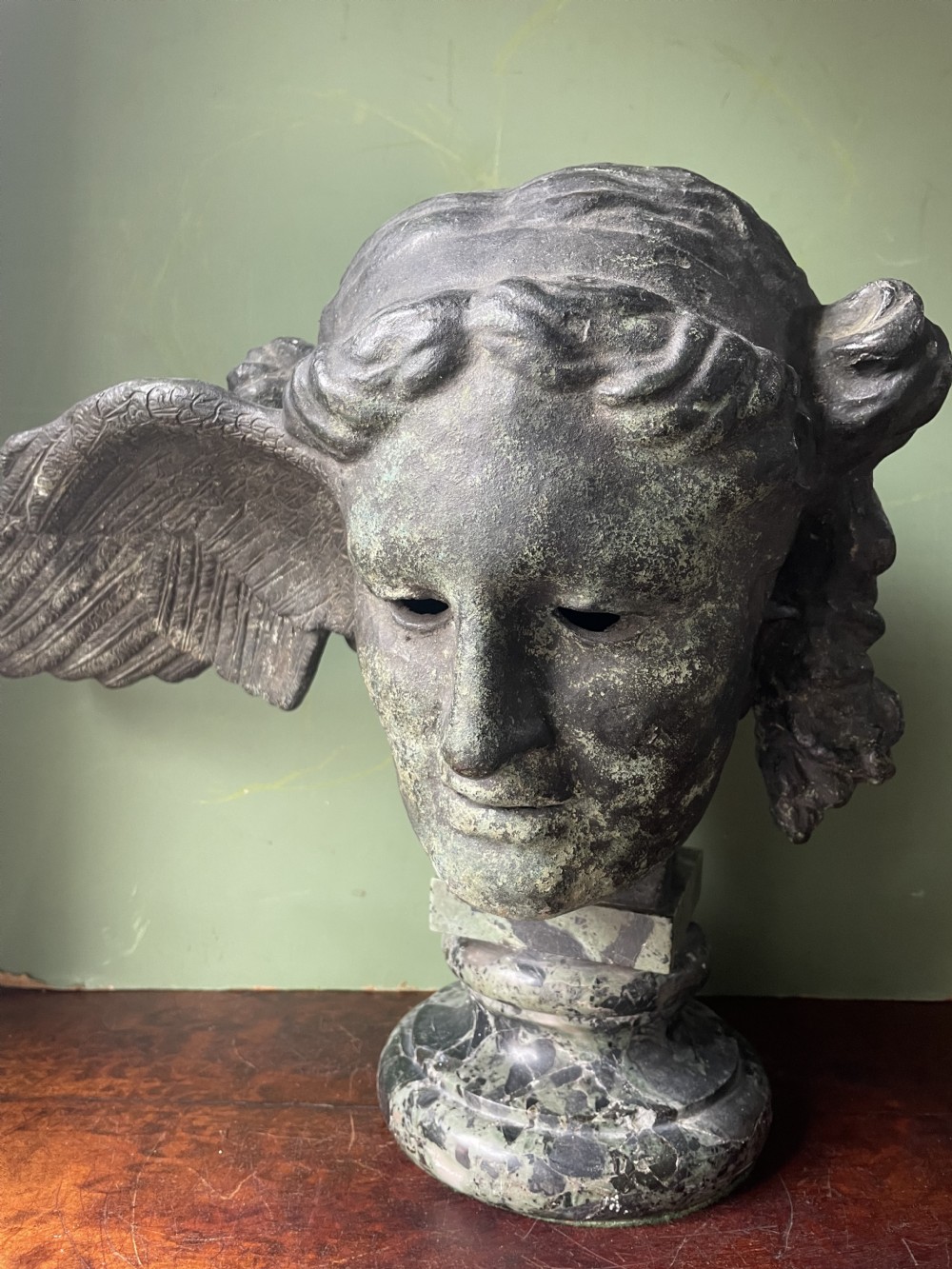 A 19th-century verdigris bronze head study of Hypnos featuring a winged temple, mounted on a round variegated green marble base. View XXI
