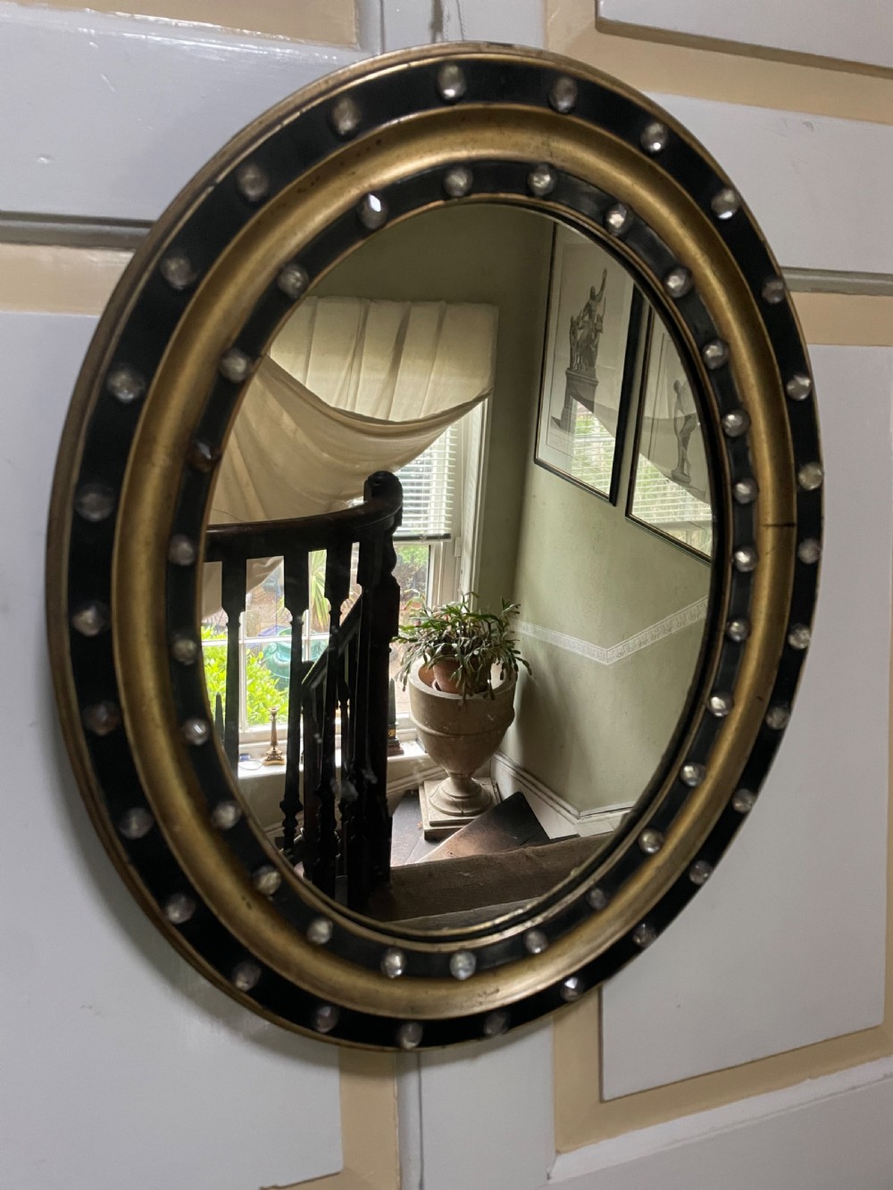 Mid C19th Irish oval mirror in ebonised and parcel-gilt moulded profile frame set with a double band of facetted cut-glass cabochons. 