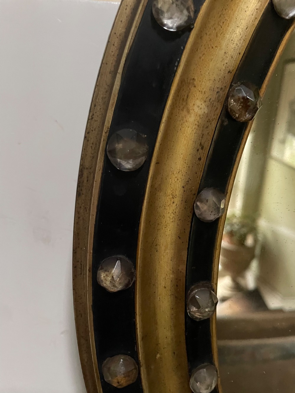Mid C19th Irish oval mirror in ebonised and parcel-gilt moulded profile frame set with a double band of facetted cut-glass cabochons.  View III