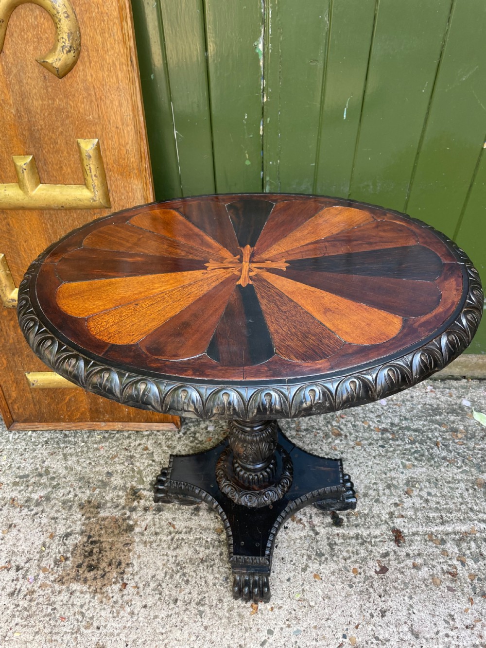 A 19th-century Anglo-Indian pedestal table featuring a carved ebony base and a starburst inlaid specimen wood top. View III