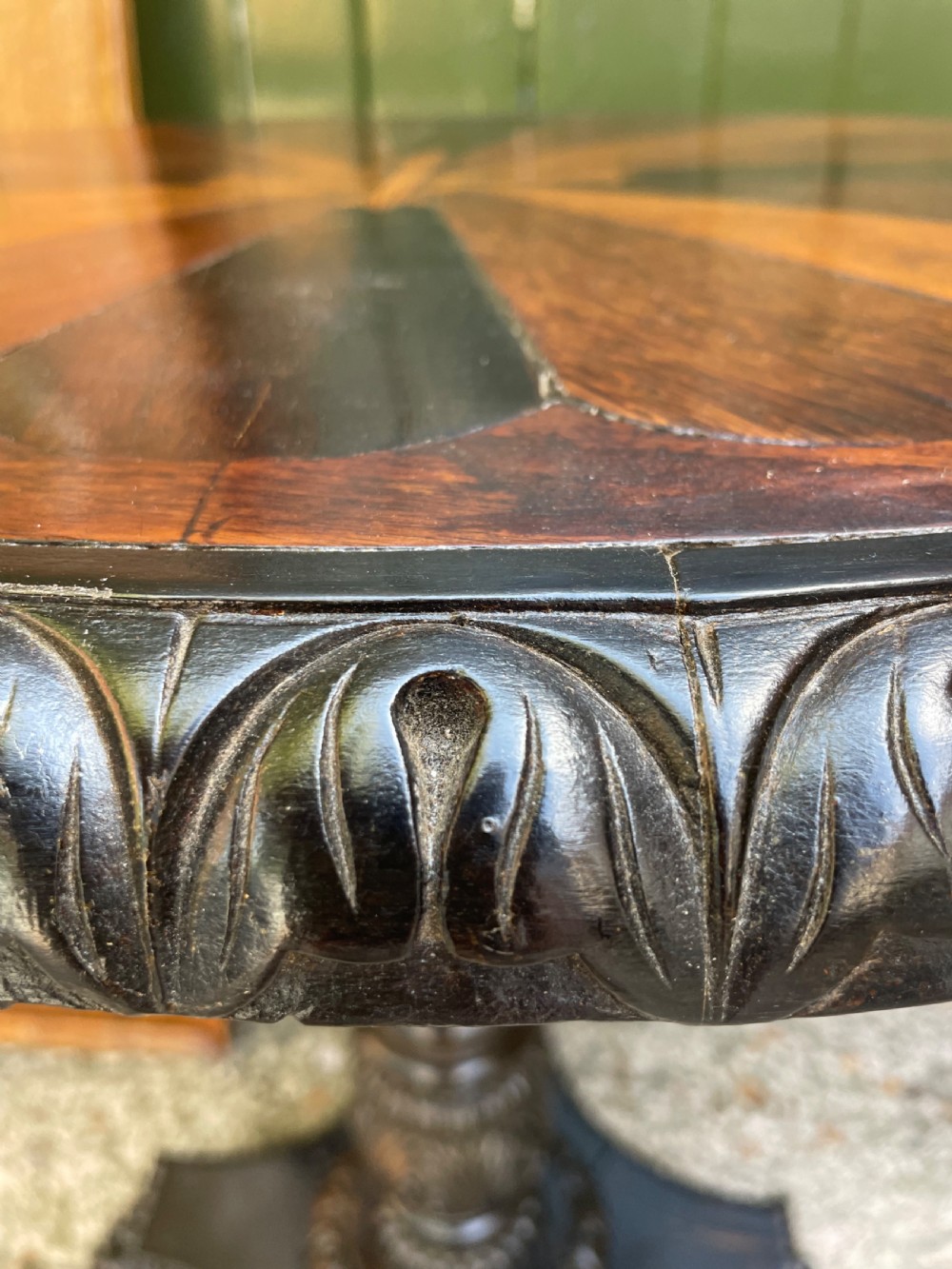 A 19th-century Anglo-Indian pedestal table featuring a carved ebony base and a starburst inlaid specimen wood top. View V