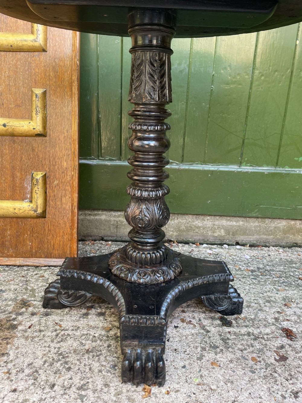 A 19th-century Anglo-Indian pedestal table featuring a carved ebony base and a starburst inlaid specimen wood top. View VI