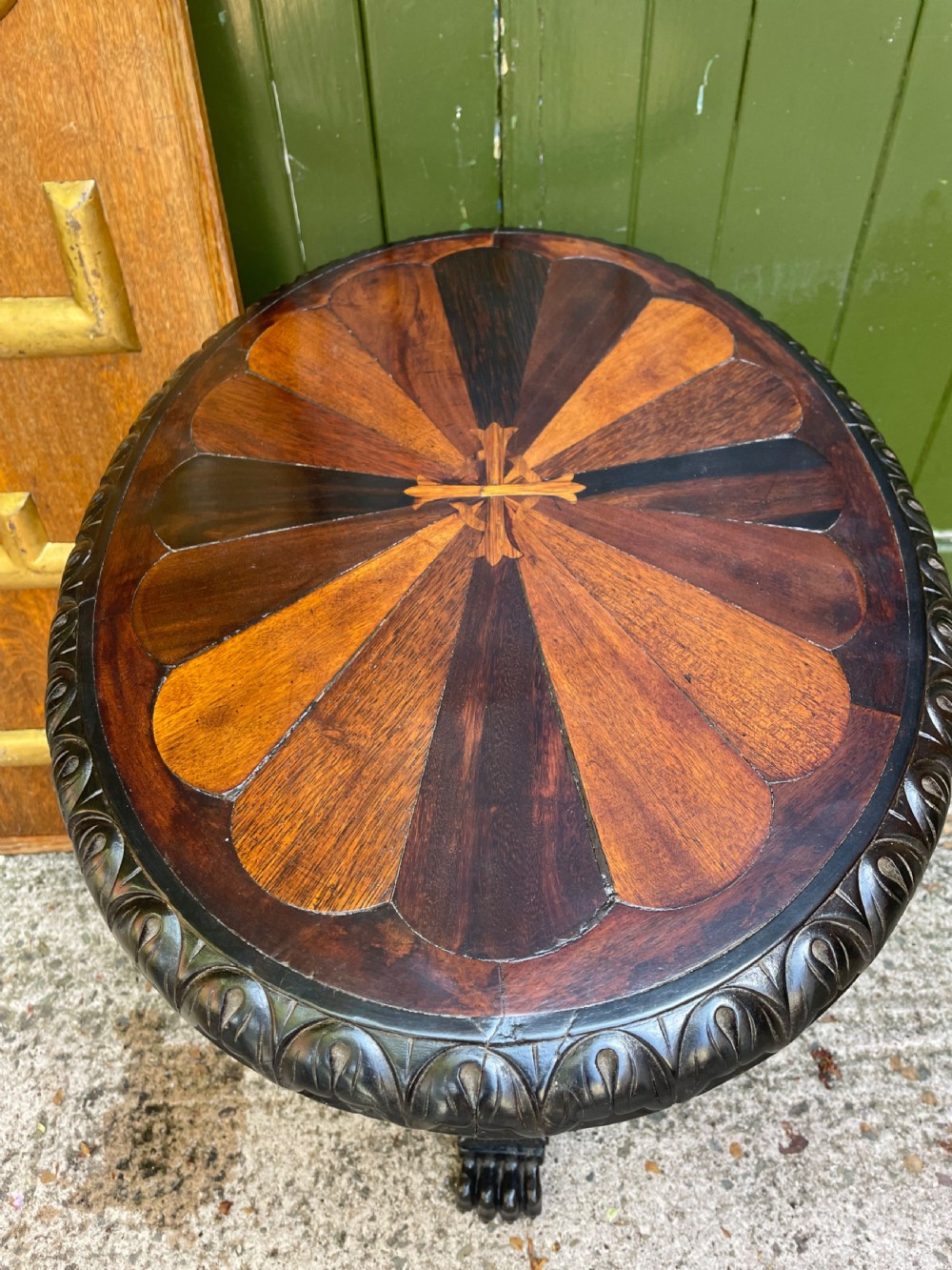 A 19th-century Anglo-Indian pedestal table featuring a carved ebony base and a starburst inlaid specimen wood top. View VIII