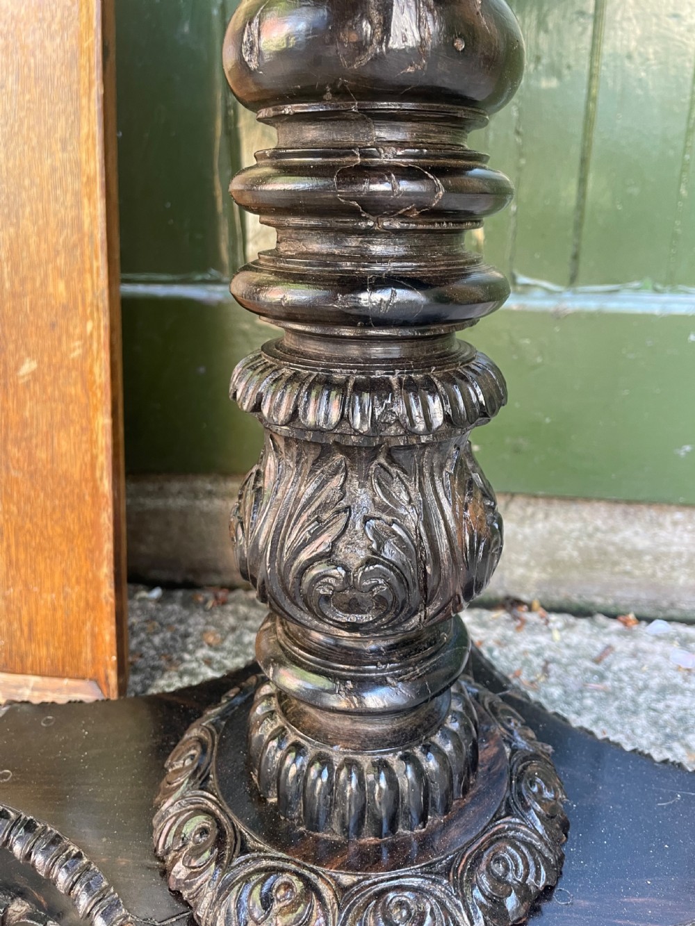 A 19th-century Anglo-Indian pedestal table featuring a carved ebony base and a starburst inlaid specimen wood top. View IX