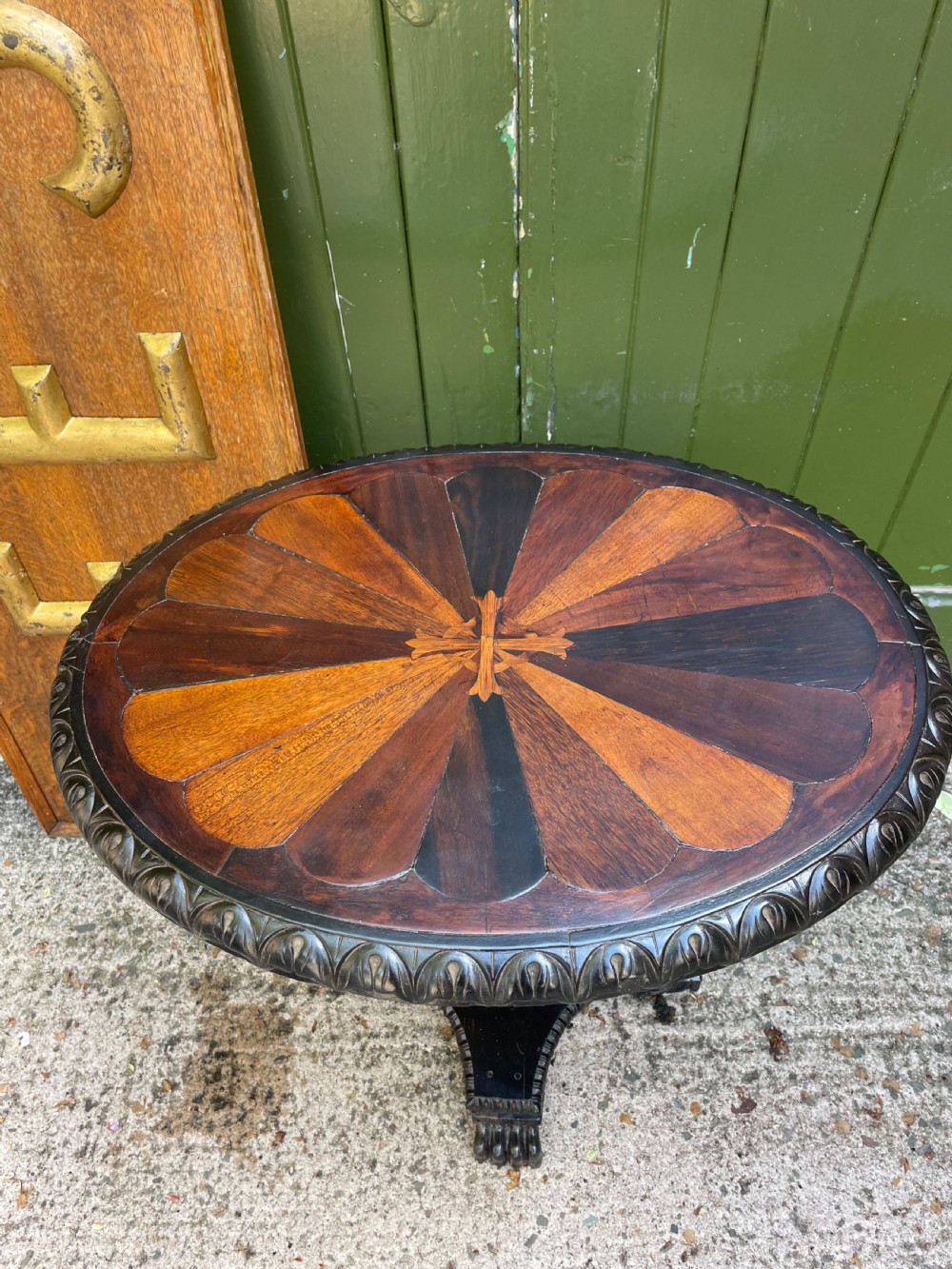 A 19th-century Anglo-Indian pedestal table featuring a carved ebony base and a starburst inlaid specimen wood top. View XI