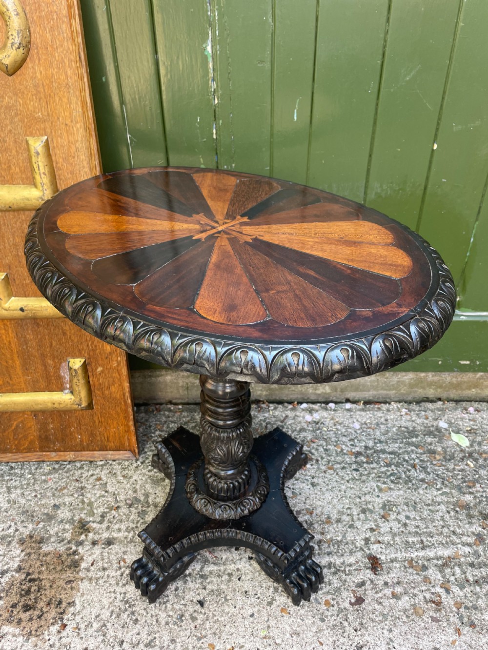 A 19th-century Anglo-Indian pedestal table featuring a carved ebony base and a starburst inlaid specimen wood top. View XIII