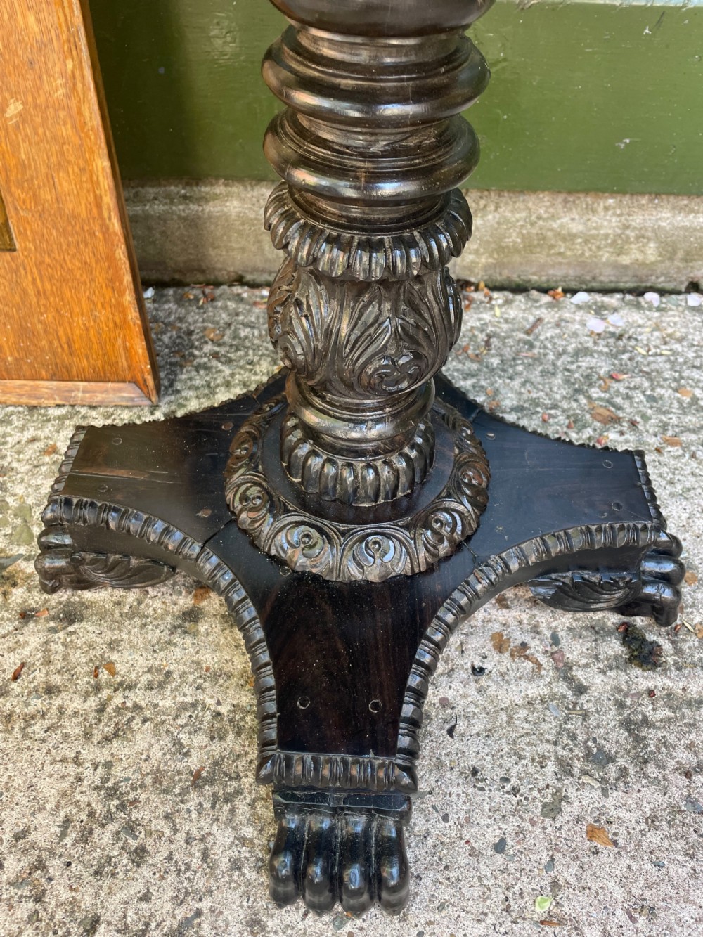 A 19th-century Anglo-Indian pedestal table featuring a carved ebony base and a starburst inlaid specimen wood top. View XVI