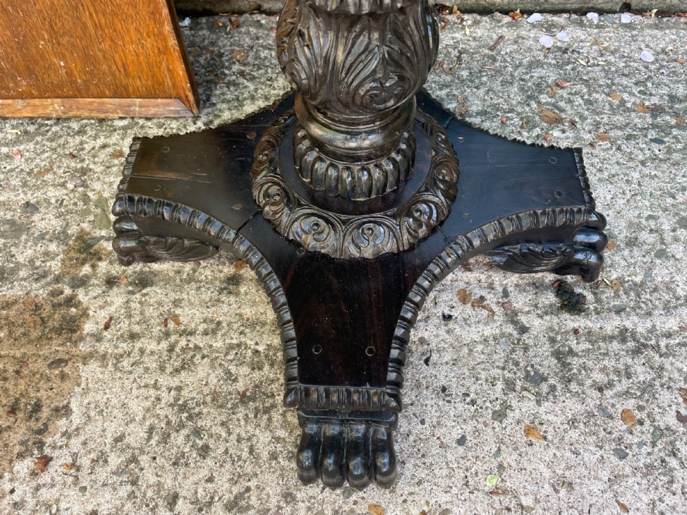 A 19th-century Anglo-Indian pedestal table featuring a carved ebony base and a starburst inlaid specimen wood top. View XVII