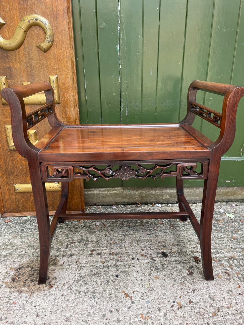 A late Qing Dynasty Chinese carved hardwood dressing stool featuring raised handles, openwork carved aprons, and square legs with stretchers. View II