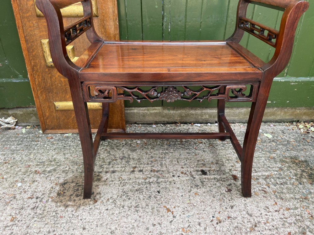 A late Qing Dynasty Chinese carved hardwood dressing stool featuring raised handles, openwork carved aprons, and square legs with stretchers. View III