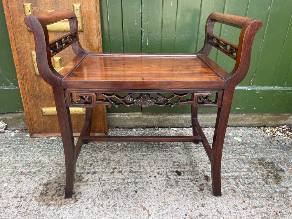A late Qing Dynasty Chinese carved hardwood dressing stool featuring raised handles, openwork carved aprons, and square legs with stretchers. View V