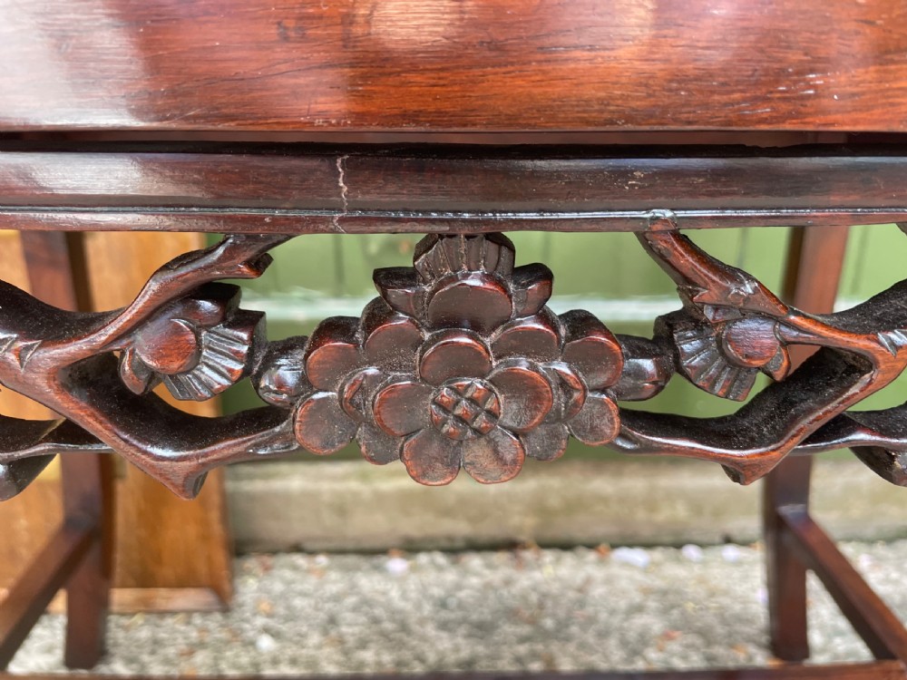 A late Qing Dynasty Chinese carved hardwood dressing stool featuring raised handles, openwork carved aprons, and square legs with stretchers. View X