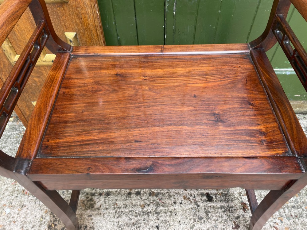 A late Qing Dynasty Chinese carved hardwood dressing stool featuring raised handles, openwork carved aprons, and square legs with stretchers. View XI