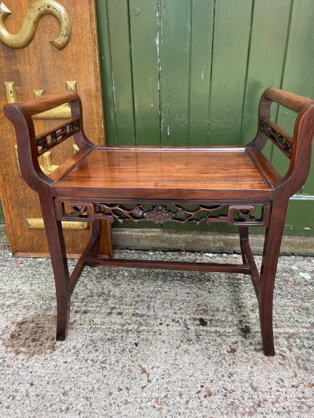 A late Qing Dynasty Chinese carved hardwood dressing stool featuring raised handles, openwork carved aprons, and square legs with stretchers. View XII