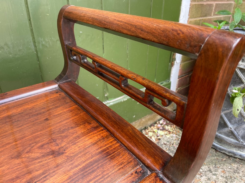 A late Qing Dynasty Chinese carved hardwood dressing stool featuring raised handles, openwork carved aprons, and square legs with stretchers. View XVI