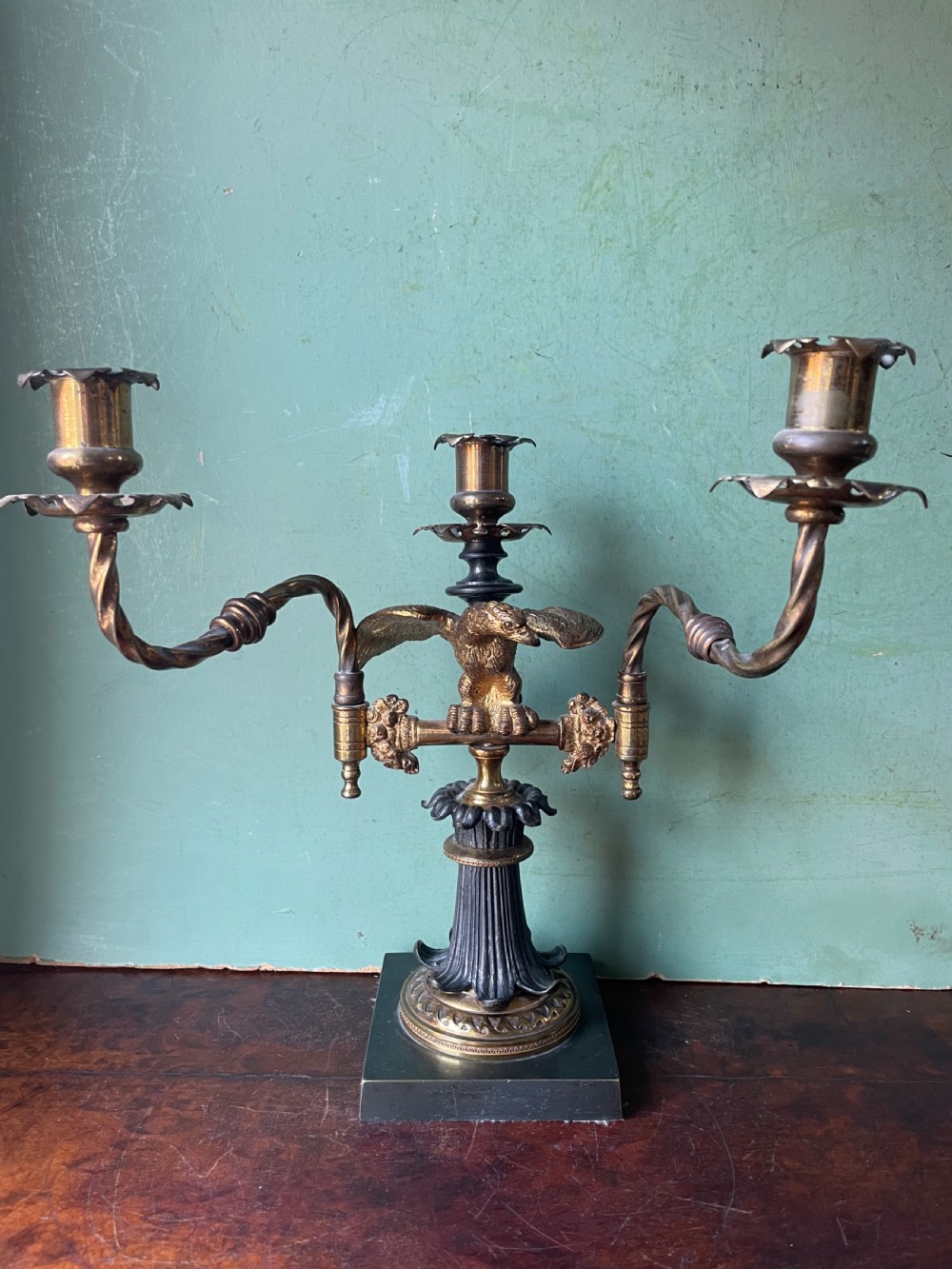An early nineteenth-century Regency period three-light candelabra featuring adjustable swivelling arms, a central eagle figure perched above a fluted bronze column, and a square plinth base. View II