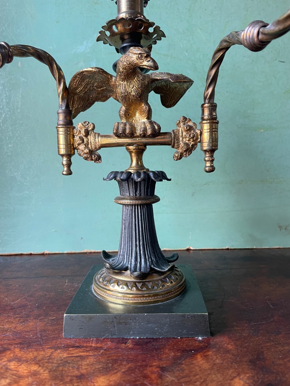 An early nineteenth-century Regency period three-light candelabra featuring adjustable swivelling arms, a central eagle figure perched above a fluted bronze column, and a square plinth base. View IV