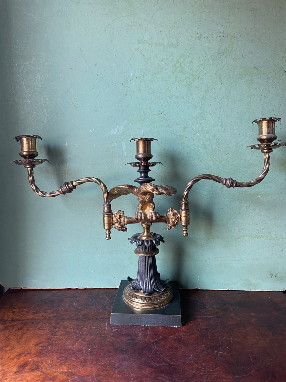 An early nineteenth-century Regency period three-light candelabra featuring adjustable swivelling arms, a central eagle figure perched above a fluted bronze column, and a square plinth base. View V