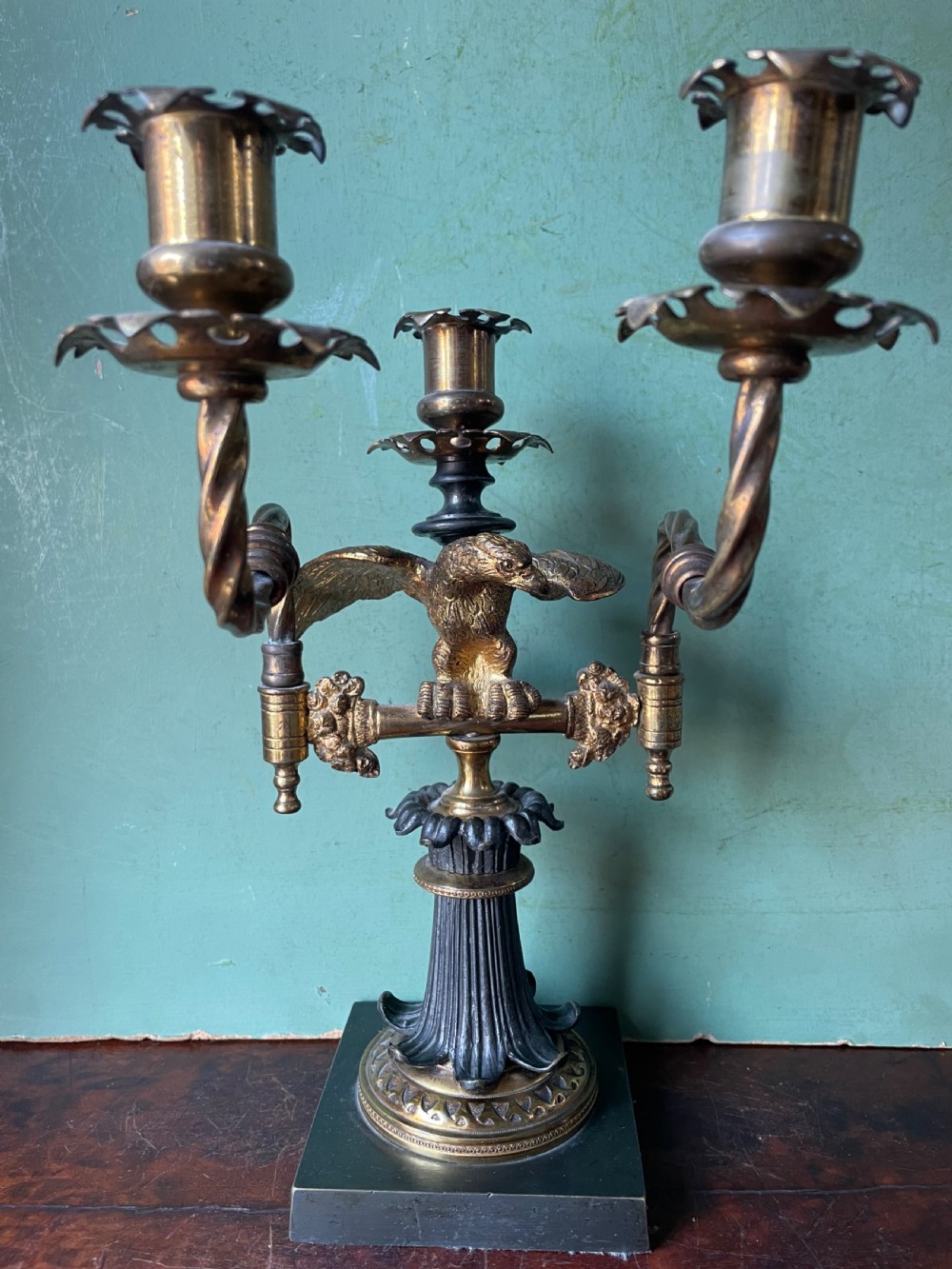 An early nineteenth-century Regency period three-light candelabra featuring adjustable swivelling arms, a central eagle figure perched above a fluted bronze column, and a square plinth base. View XI