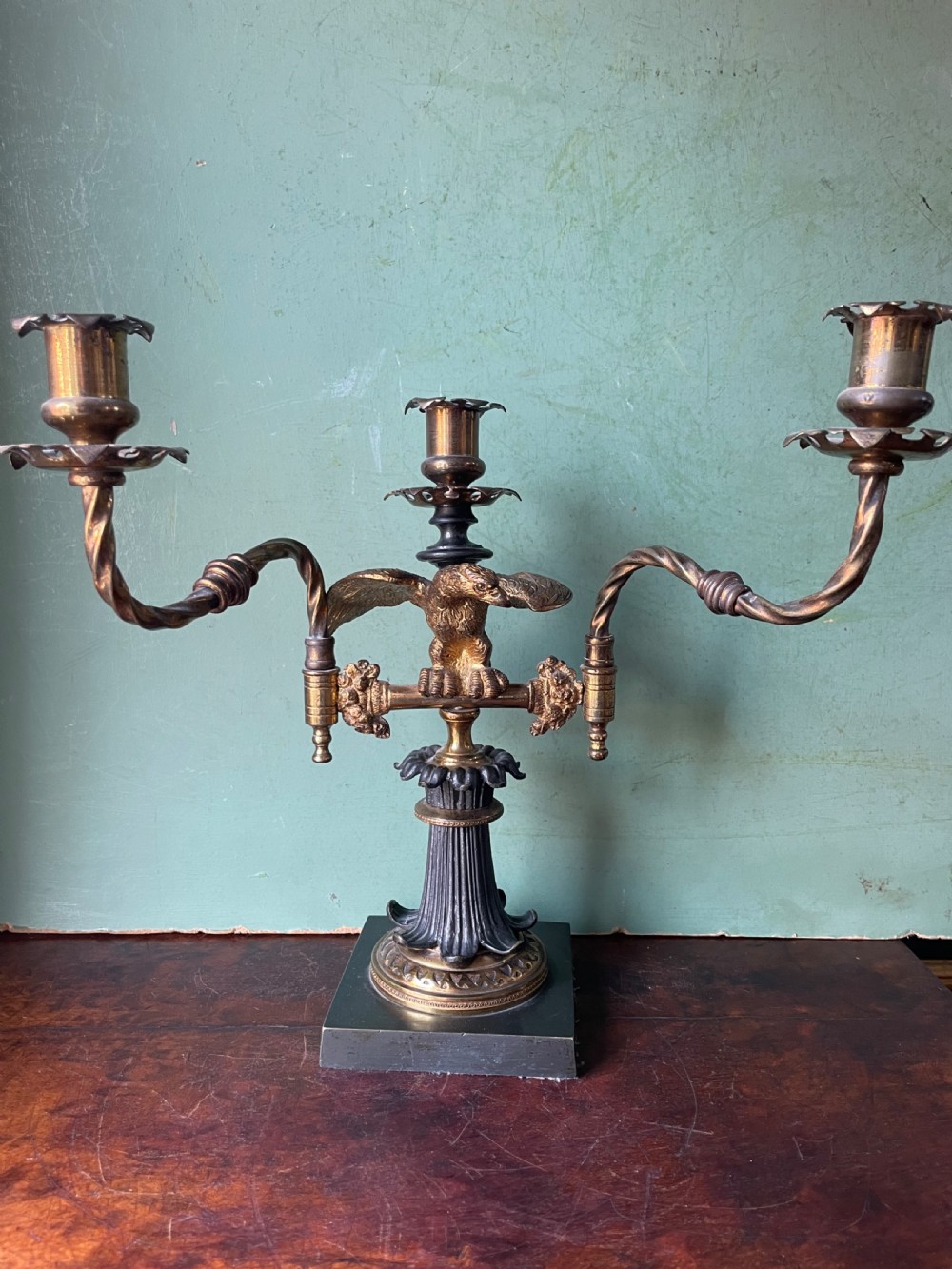 An early nineteenth-century Regency period three-light candelabra featuring adjustable swivelling arms, a central eagle figure perched above a fluted bronze column, and a square plinth base. View XII