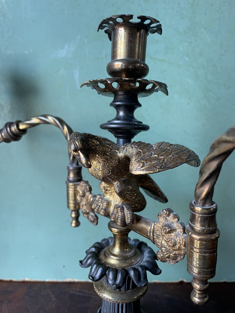 An early nineteenth-century Regency period three-light candelabra featuring adjustable swivelling arms, a central eagle figure perched above a fluted bronze column, and a square plinth base. View XVI