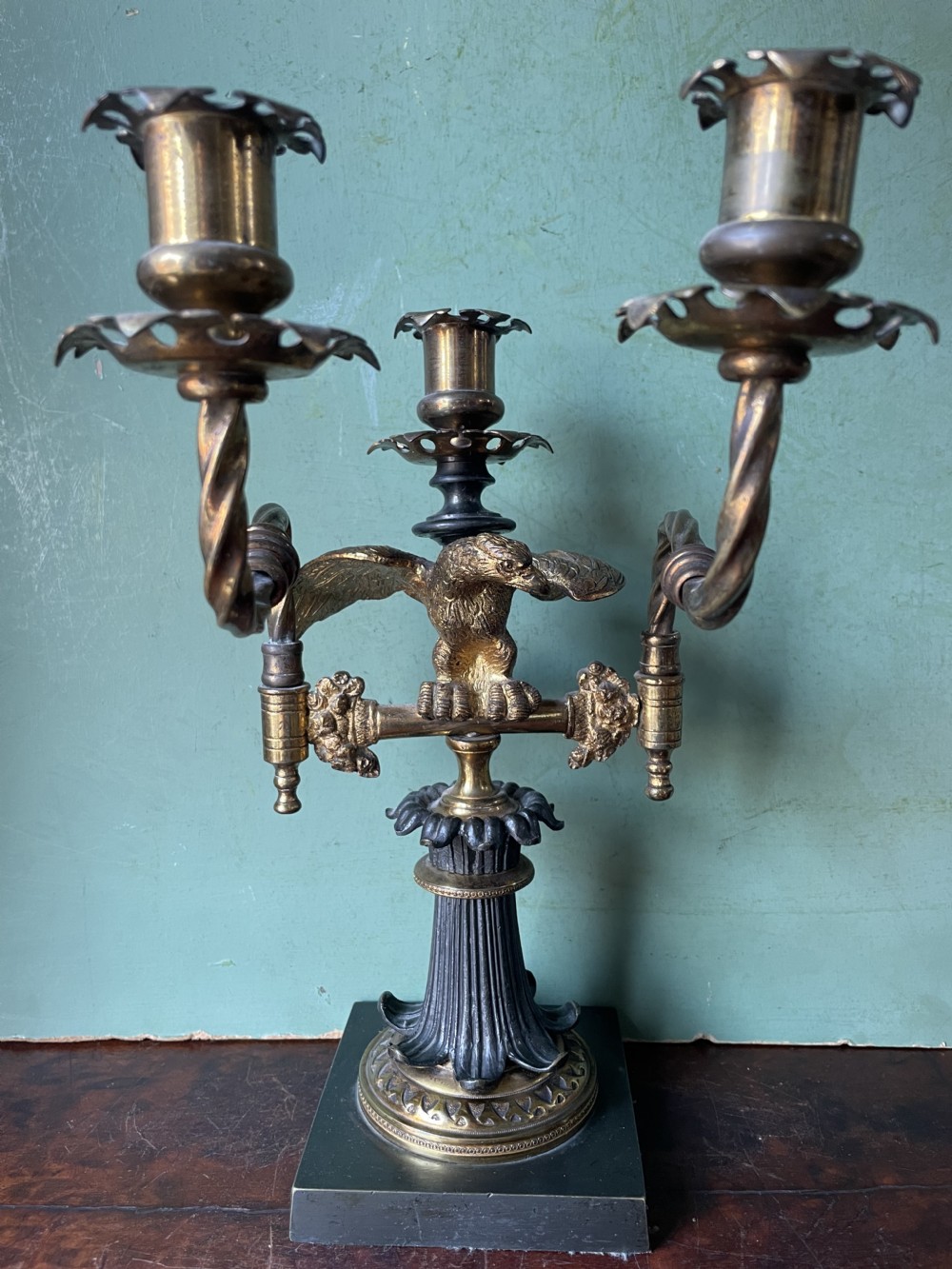 An early nineteenth-century Regency period three-light candelabra featuring adjustable swivelling arms, a central eagle figure perched above a fluted bronze column, and a square plinth base. View XVIII
