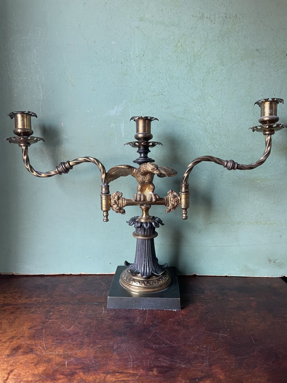 An early nineteenth-century Regency period three-light candelabra featuring adjustable swivelling arms, a central eagle figure perched above a fluted bronze column, and a square plinth base. View XXI
