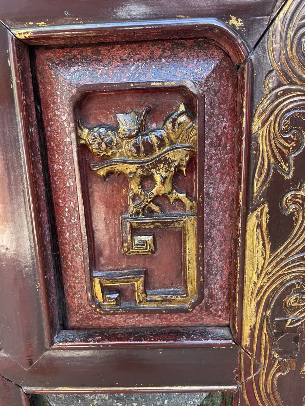 A late nineteenth-century Chinese Qing Dynasty red lacquered side cabinet featuring relief-carved gilded wood panels depicted with architectural scenes, figures, and foliage. View VIII