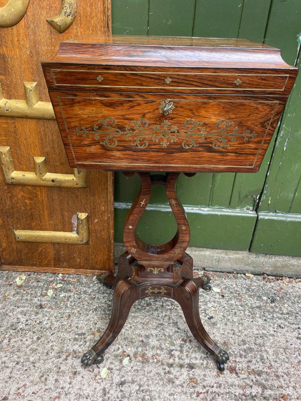 An early 19th-century Regency rosewood teapoy featuring floral brass inlay, a lyre-shaped stem support, and quadruped splayed legs with brass claw feet. View II