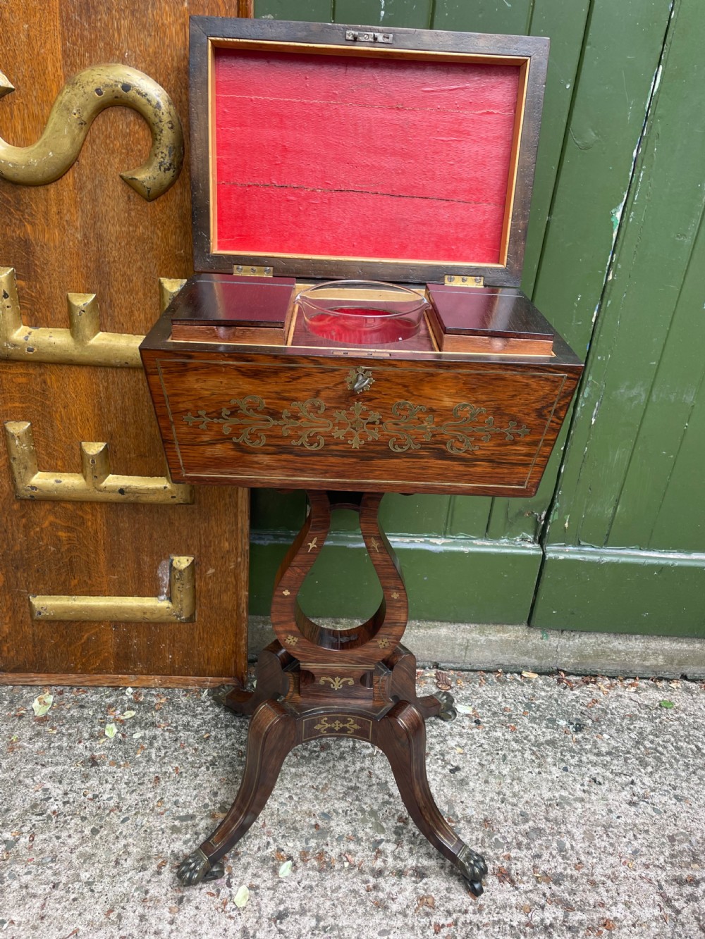An early 19th-century Regency rosewood teapoy featuring floral brass inlay, a lyre-shaped stem support, and quadruped splayed legs with brass claw feet. View VII