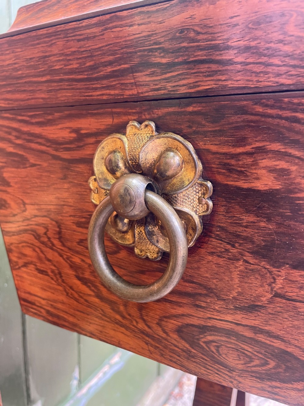 An early 19th-century Regency rosewood teapoy featuring floral brass inlay, a lyre-shaped stem support, and quadruped splayed legs with brass claw feet. View X