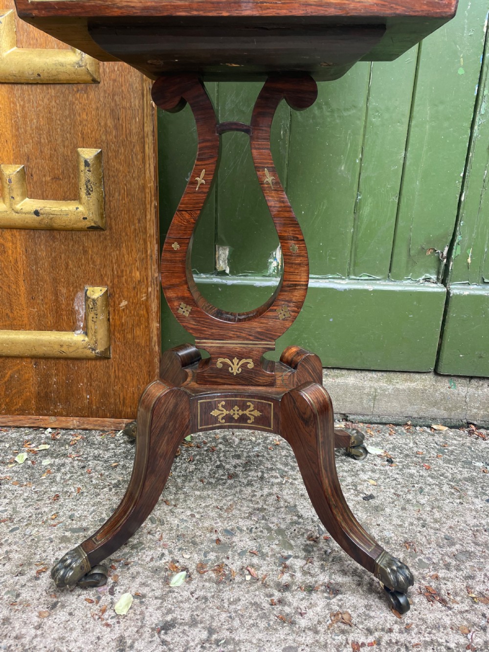 An early 19th-century Regency rosewood teapoy featuring floral brass inlay, a lyre-shaped stem support, and quadruped splayed legs with brass claw feet. View XI