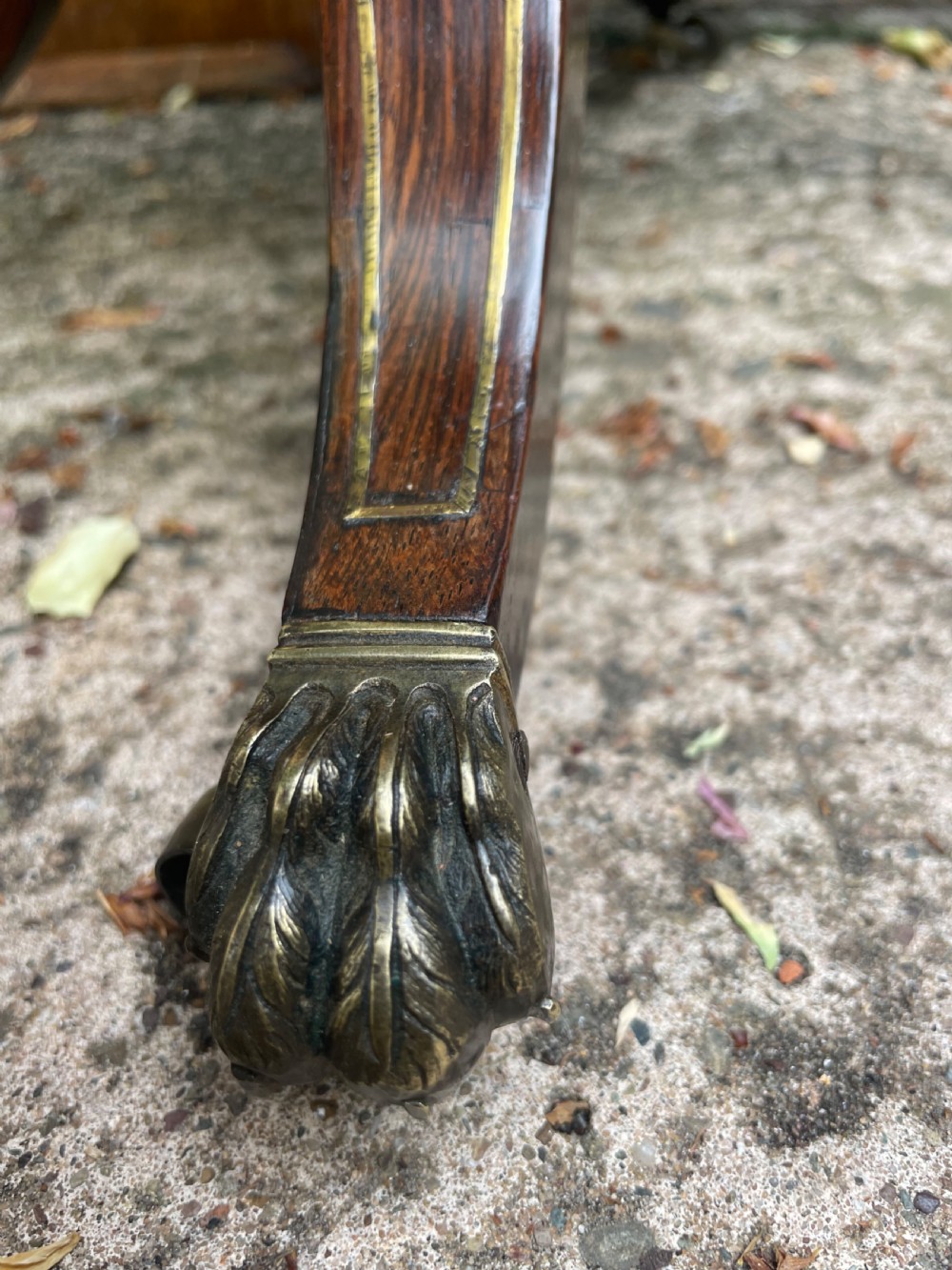 An early 19th-century Regency rosewood teapoy featuring floral brass inlay, a lyre-shaped stem support, and quadruped splayed legs with brass claw feet. View XVI