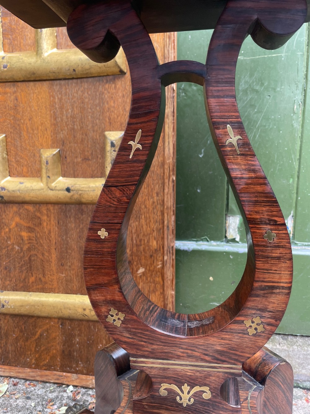 An early 19th-century Regency rosewood teapoy featuring floral brass inlay, a lyre-shaped stem support, and quadruped splayed legs with brass claw feet. View XIX