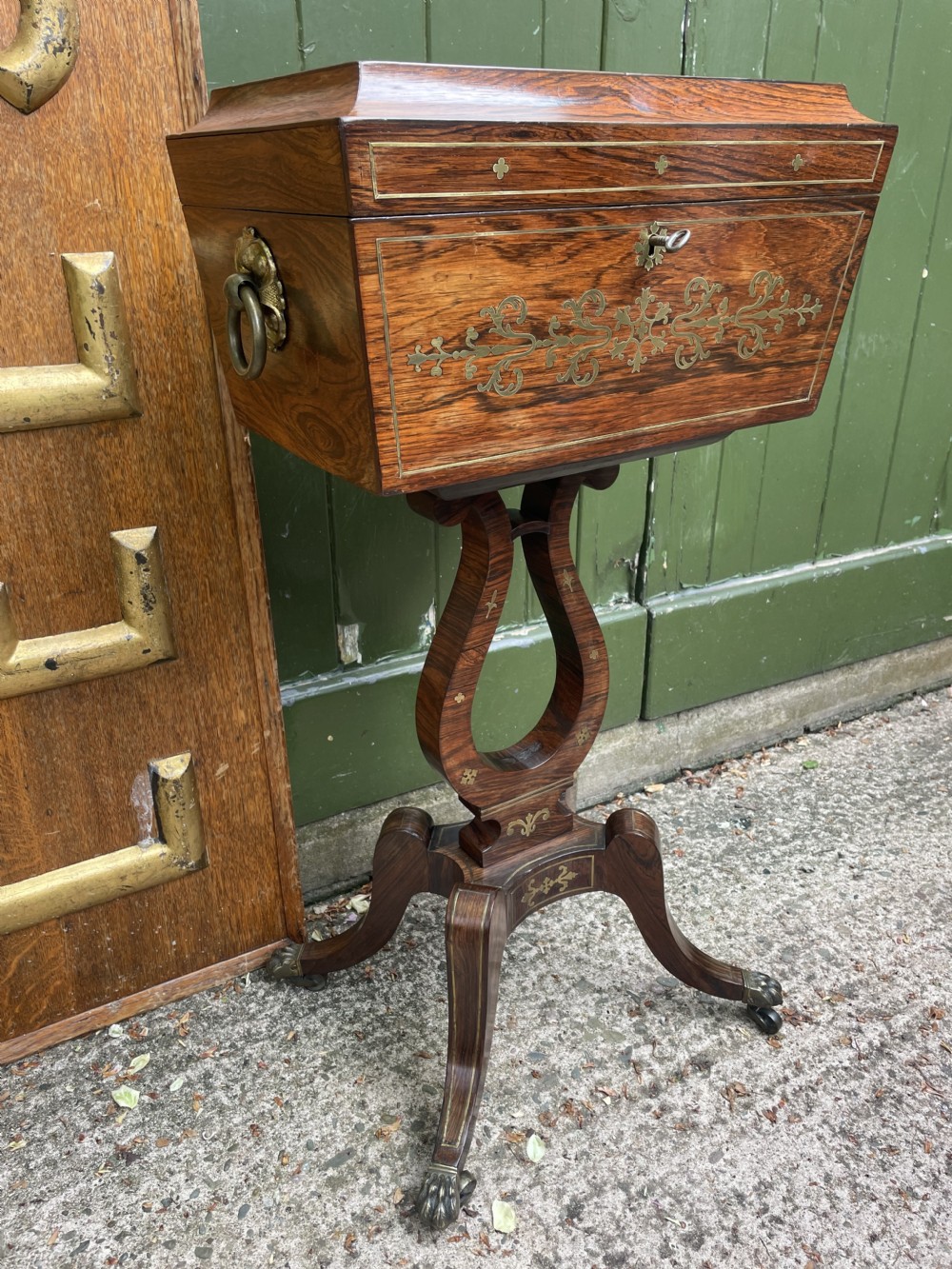 An early 19th-century Regency rosewood teapoy featuring floral brass inlay, a lyre-shaped stem support, and quadruped splayed legs with brass claw feet. View XXI