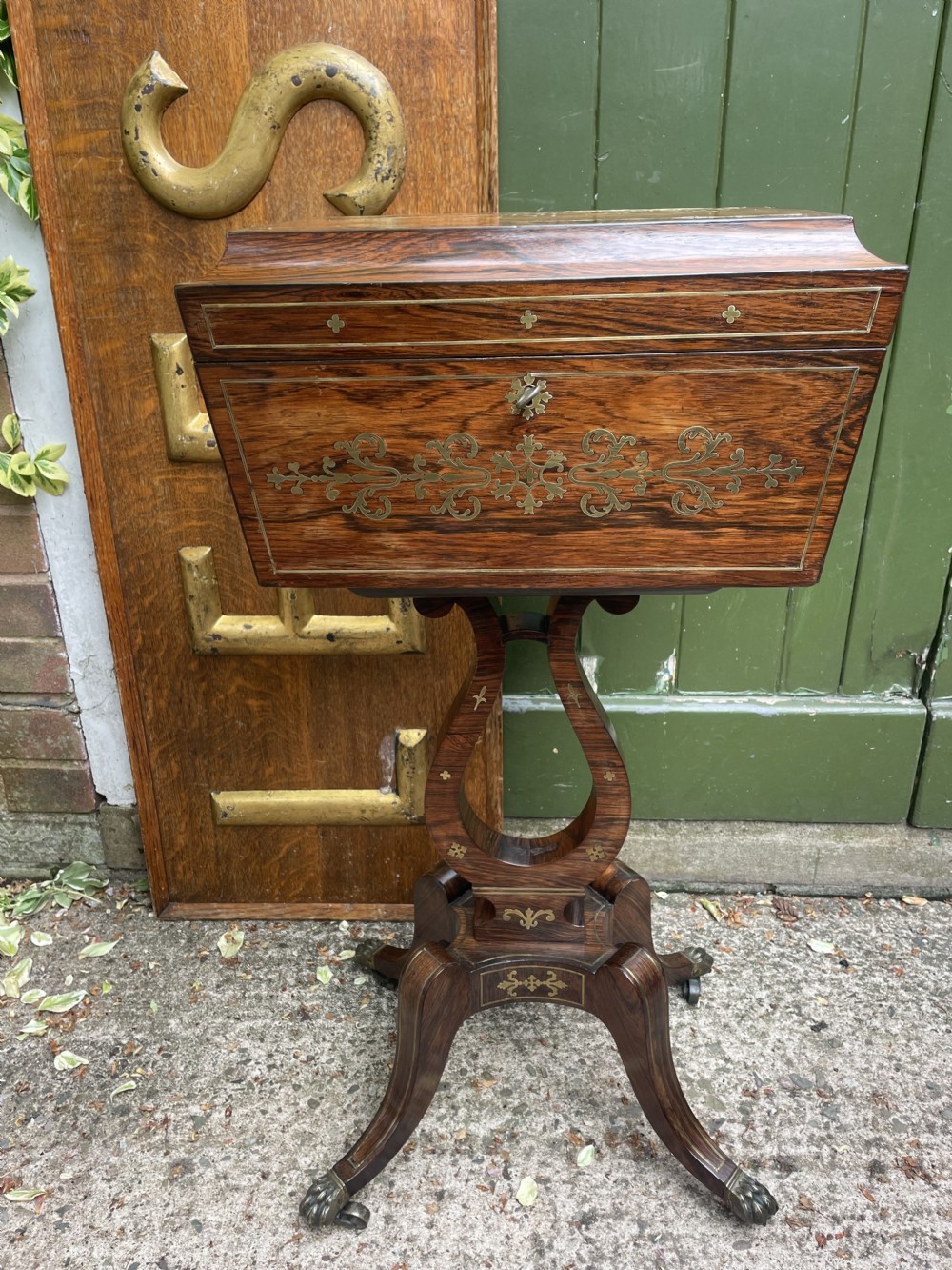 An early 19th-century Regency rosewood teapoy featuring floral brass inlay, a lyre-shaped stem support, and quadruped splayed legs with brass claw feet. View XVII