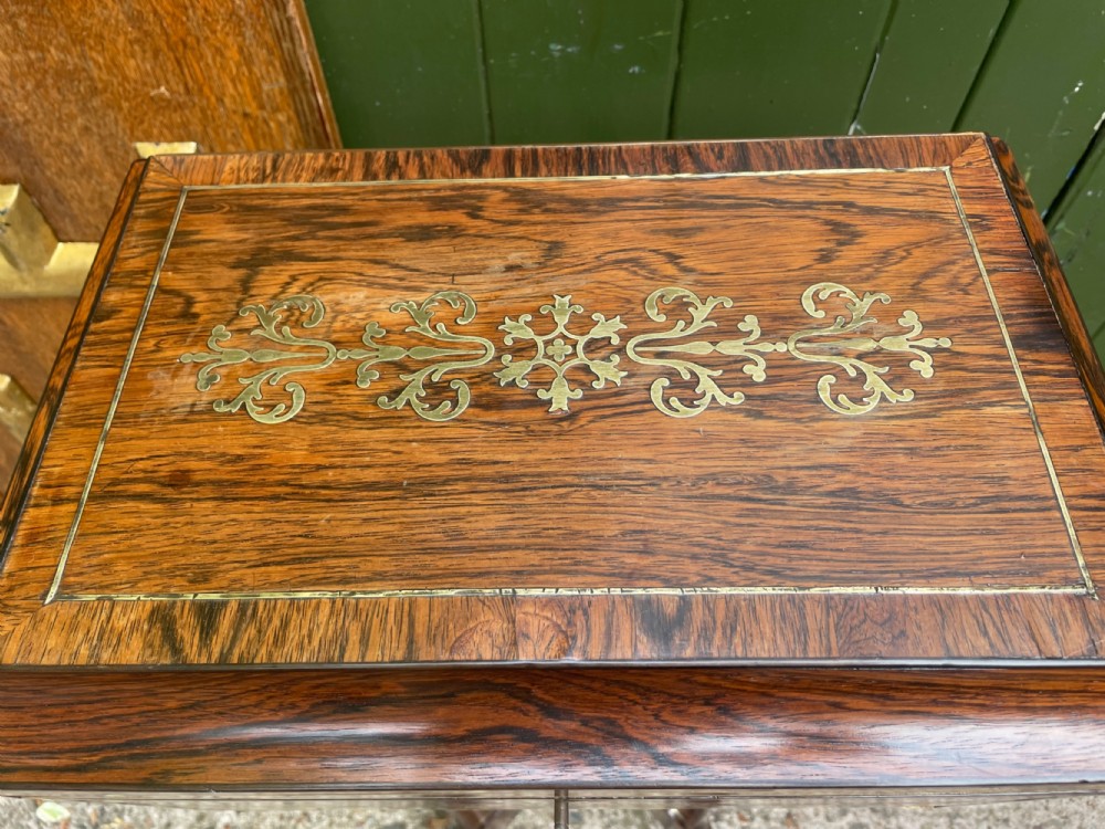 An early 19th-century Regency rosewood teapoy featuring floral brass inlay, a lyre-shaped stem support, and quadruped splayed legs with brass claw feet. View IX