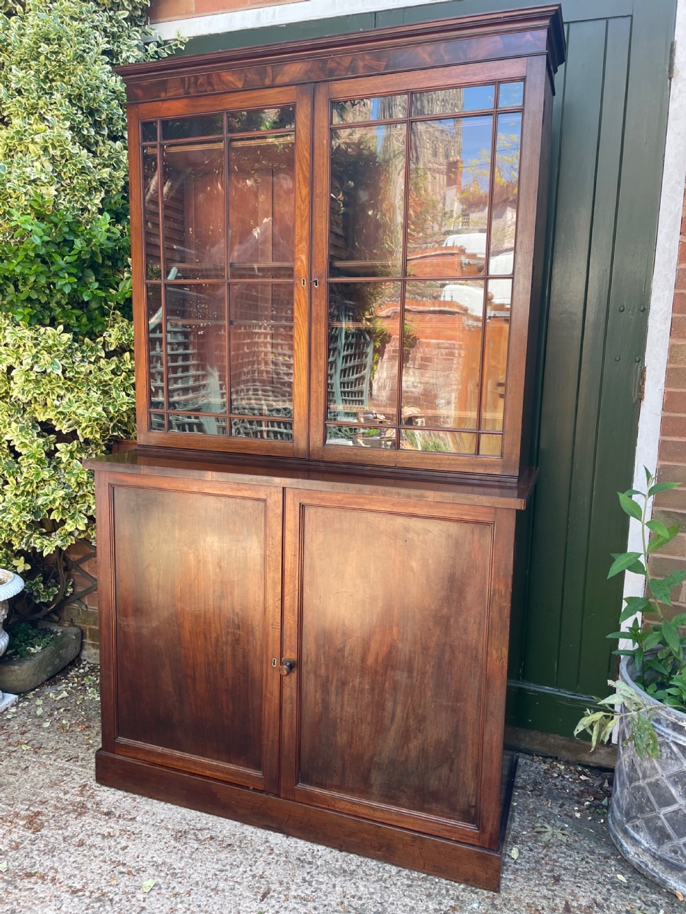 An early nineteenth-century mahogany library bookcase featuring astragal-glazed upper doors and double panelled lower doors.