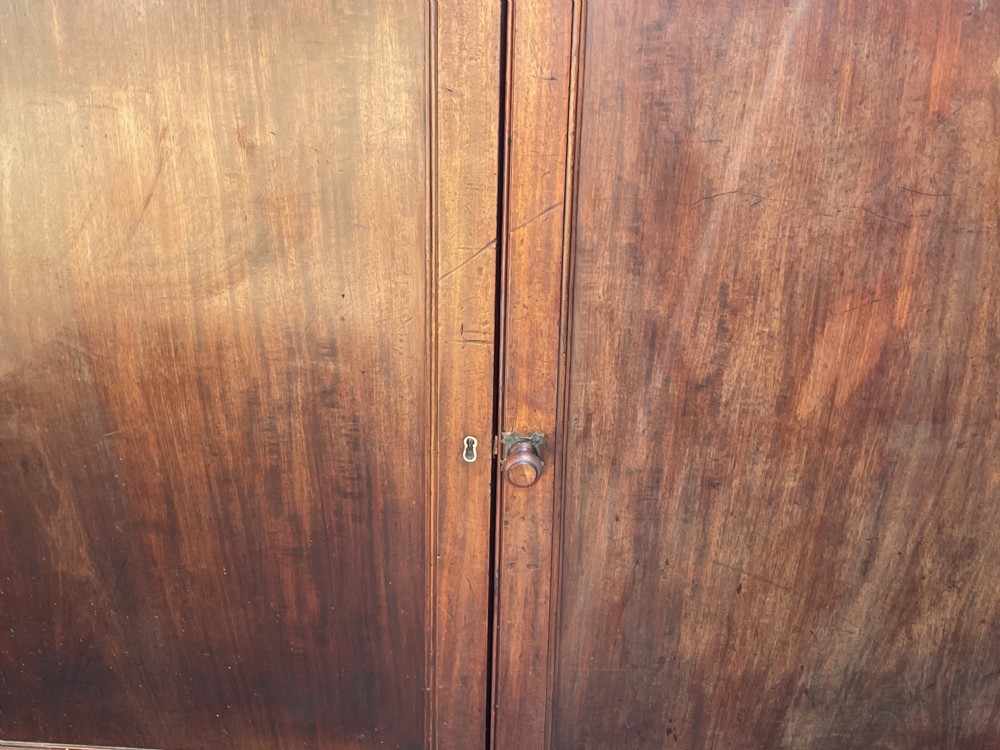 An early nineteenth-century mahogany library bookcase featuring astragal-glazed upper doors and double panelled lower doors. View XXVI